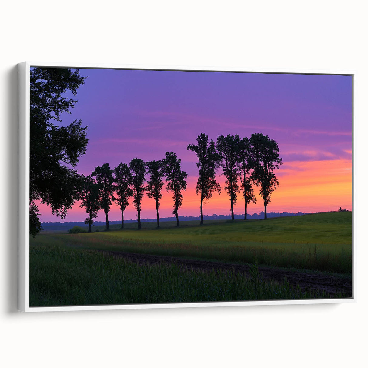 Framed canvas artwork depicting a serene countryside landscape with rolling hills and lush greenery, presented in a sleek white frame for a modern touch.