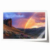 Desert landscape rolled print showcasing vibrant orange and brown hues, featuring rugged mountains and a clear blue sky, packaged securely in a cardboard tube for easy transport.