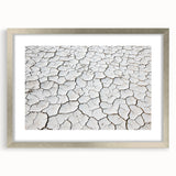 Framed desert landscape art print in a silver frame with a mat, showcasing warm earthy tones and intricate details, perfect for home decor enhancement.