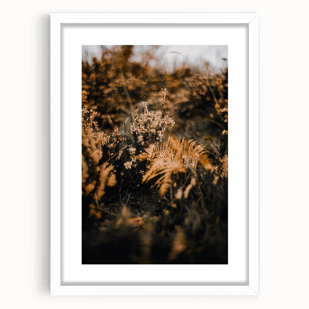 Abstract art print depicting fall scenery in muted orange and brown tones, framed with a white mat.