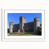 Framed landscape artwork showcasing a majestic castle set against a serene backdrop, featuring a white mat and elegant detailing, perfect for home decor.