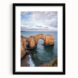 Framed black landscape artwork showcasing dramatic cliffs against a serene sky, enhancing home decor with a sophisticated touch and elegant matting.