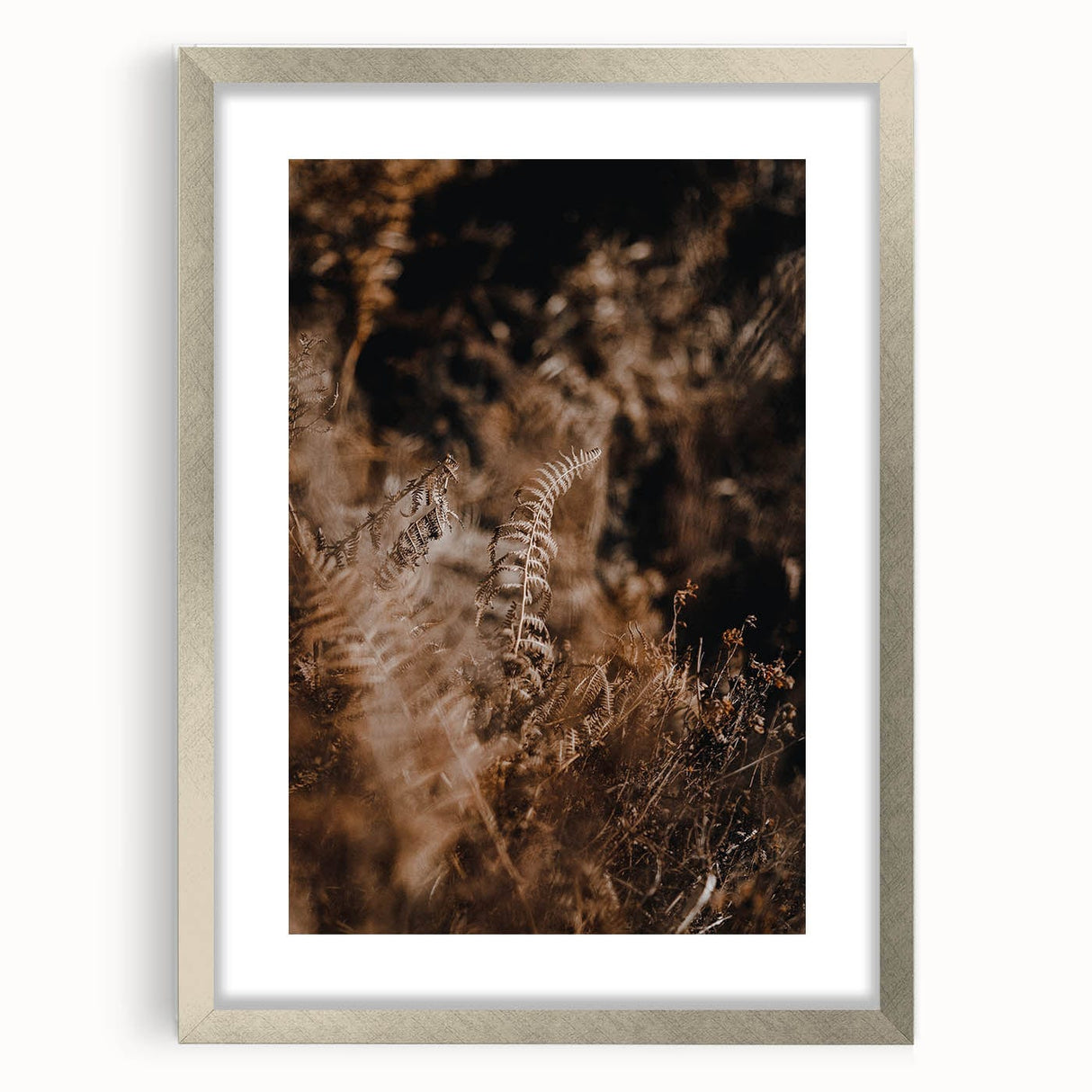 Textured abstract art print in warm autumnal hues on a silver-framed canvas, ideal for bedroom decor.