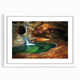 Framed landscape artwork depicting a serene cave scene with vibrant colors, elegantly matted in white, perfect for home decor and enhancing any living space.