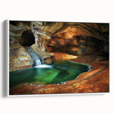 Framed canvas artwork depicting a serene landscape with caves and natural formations. The piece features earthy tones and a white frame, ideal for modern home decor.