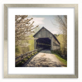 Textured abstract art print of a covered bridge in muted earth tones on a framed silver mat, suitable for bedroom decor.