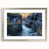 Framed landscape artwork depicting vibrant canyons in shades of orange and red, set in a sleek silver frame with matting, ideal for home decor.