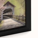 Close-up of a black framed canvas depicting a covered bridge in textured, colorful art.