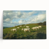 Stretched canvas depicting a serene countryside landscape with vibrant green fields and a clear blue sky, leaning against a textured wall, ideal for home decor.