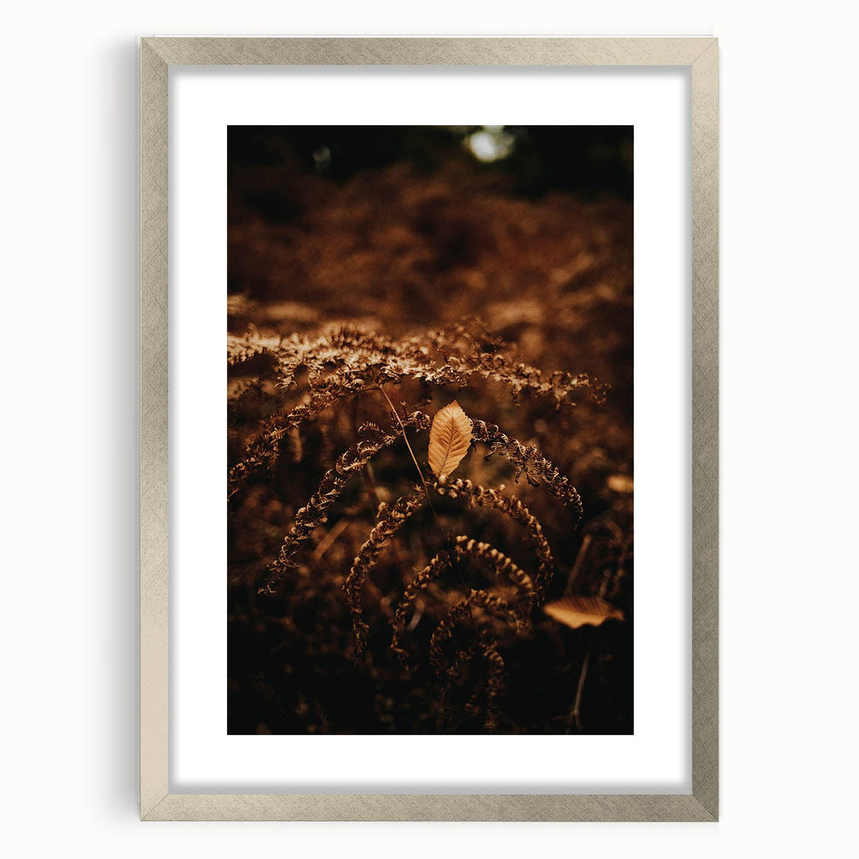 Textured abstract art print in warm autumn hues on a silver-framed canvas, suitable for bedroom decor.