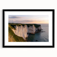 Framed landscape artwork depicting dramatic cliffs under a vibrant sunset, featuring a sleek black frame and white mat, perfect for home decor enhancement.