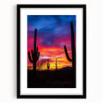 Framed desert landscape artwork in a sleek black frame, showcasing vibrant hues of orange and yellow against a serene blue sky, perfect for modern decor.