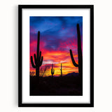Framed desert landscape artwork in a sleek black frame, showcasing vibrant hues of orange and yellow against a serene blue sky, perfect for modern decor.