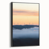 Framed canvas artwork depicting a serene countryside landscape with vibrant green fields and a clear blue sky, featuring a sleek black frame that enhances its beauty.