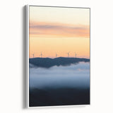 Framed canvas artwork showcasing a serene countryside landscape with rolling hills and a vibrant sunset, presented in a sleek white frame for modern decor.