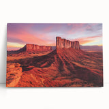 Vibrant stretched canvas artwork depicting a stunning desert landscape with warm hues of orange and yellow, elegantly leaning against a neutral wall. Perfect for modern home decor.