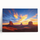 Stretched canvas artwork depicting a vibrant desert landscape with warm hues of orange and yellow, leaning against a neutral wall, ideal for home decor.
