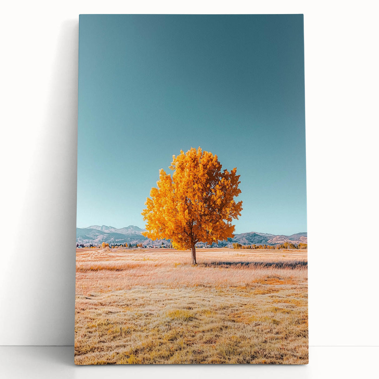 Stretched canvas artwork depicting vibrant green fields under a clear blue sky, leaning against a rustic wooden wall, ideal for home decor or office spaces.
