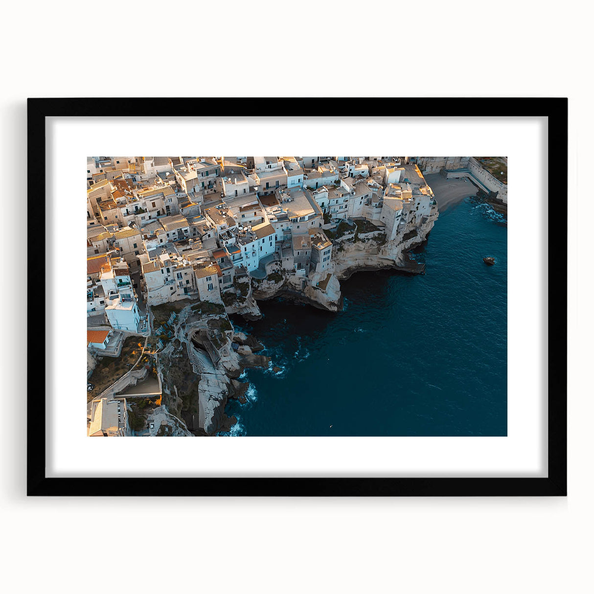 Framed landscape artwork showcasing dramatic cliffs against a vibrant sunset, presented in a sleek black frame with a white mat, perfect for modern decor.