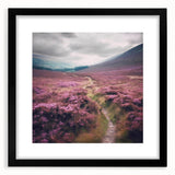 Framed landscape wall art depicting a serene countryside scene, featuring vibrant greens and blues, with a sleek black frame and white matting, perfect for home décor.