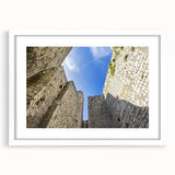 Framed landscape artwork showcasing a majestic castle, surrounded by lush greenery and a clear sky, presented in a white mat for a refined look. Perfect for home decor.
