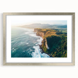 Framed landscape art showcasing dramatic cliffs and serene ocean views, featuring a sleek silver mat, perfect for enhancing modern decor.