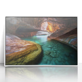 Framed acrylic artwork depicting a vibrant landscape of canyons with rich colors and intricate details, set against a sleek white frame to enhance any decor.