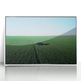 Framed acrylic art piece showcasing a serene countryside landscape with vibrant green fields and a clear blue sky, elegantly displayed in a white frame.