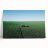Stretched canvas artwork depicting a serene countryside landscape, featuring lush green fields, rolling hills, and a clear blue sky, perfect for home decor.