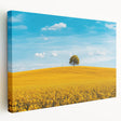 Stretched canvas artwork depicting a serene countryside landscape with rolling hills, vibrant green fields, and a clear blue sky, perfect for home decor.