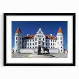 Framed landscape artwork depicting a picturesque castle surrounded by lush greenery, set in a sleek black frame with a white mat, ideal for home decor.