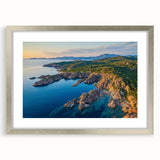 Framed landscape artwork showcasing rugged cliffs and serene natural scenery, featuring a sleek silver mat, perfect for enhancing home decor.