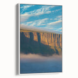 Framed canvas artwork depicting a scenic landscape of rugged cliffs under a clear blue sky, presented in a sleek white frame, ideal for modern home decor.