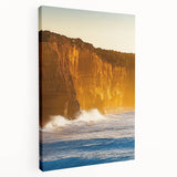 Stretched canvas artwork depicting a dramatic cliffside landscape at sunset, showcasing vibrant hues of orange and purple against a serene sky, ideal for home decor.