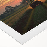 Rolled canvas artwork depicting a serene countryside landscape with vibrant green fields and a clear blue sky, elegantly packaged in a protective cardboard tube for delivery.