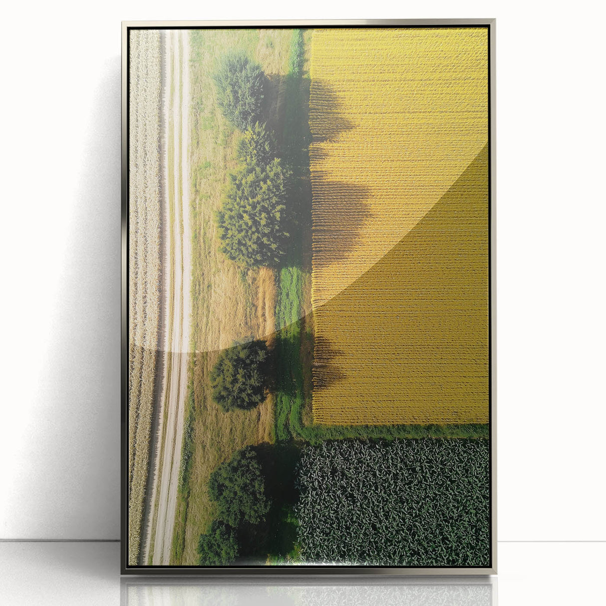 Framed acrylic artwork showcasing a serene countryside landscape with lush green fields and a blue sky, set in a sleek silver frame for a modern touch.