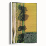 Framed canvas artwork showcasing a serene countryside landscape with vibrant green fields and a clear blue sky, displayed in a stylish white frame for an elegant touch.