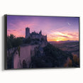 Framed canvas artwork depicting a picturesque landscape with a majestic castle, highlighted by vibrant colors and intricate details, set against a black frame.