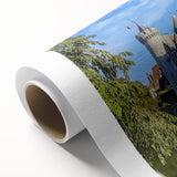 Rolled canvas artwork depicting a serene landscape with an ancient castle surrounded by lush greenery and a clear blue sky, ideal for home decor.