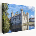 Stretched canvas artwork depicting a serene landscape with a majestic castle surrounded by lush greenery and a clear blue sky, ideal for home decor.