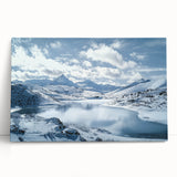 Stretched canvas art depicting a serene countryside landscape with rolling hills and a vibrant blue sky, leaning against a rustic wall, ideal for home decor.