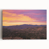 Stretched canvas artwork depicting a vibrant desert landscape at sunset, showcasing warm hues of orange and purple with rugged terrain, perfect for home décor.