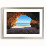 Silver-framed landscape artwork depicting a serene beach scene with gentle waves and soft sand, displayed with a white mat for an elegant presentation.