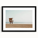 Black framed landscape artwork showcasing a serene beach scene with soft waves and golden sand, elegantly matted for a sophisticated display. Perfect for coastal decor.