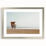 Silver-framed landscape artwork showcasing a serene beach scene with gentle waves and a clear blue sky, perfect for coastal home decor.