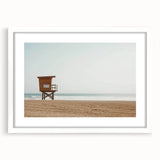 Framed landscape artwork depicting a serene beach scene with soft waves and a clear blue sky, featuring a white mat for an elegant presentation. Ideal for coastal decor.