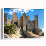Framed canvas artwork depicting a serene landscape with a majestic castle surrounded by lush greenery, showcased from a side view against a white backdrop.