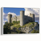 Framed canvas artwork depicting a picturesque landscape featuring a majestic castle surrounded by lush greenery, viewed from the side. The design incorporates vibrant colors, adding a serene ambiance, ideal for home decor enthusiasts.