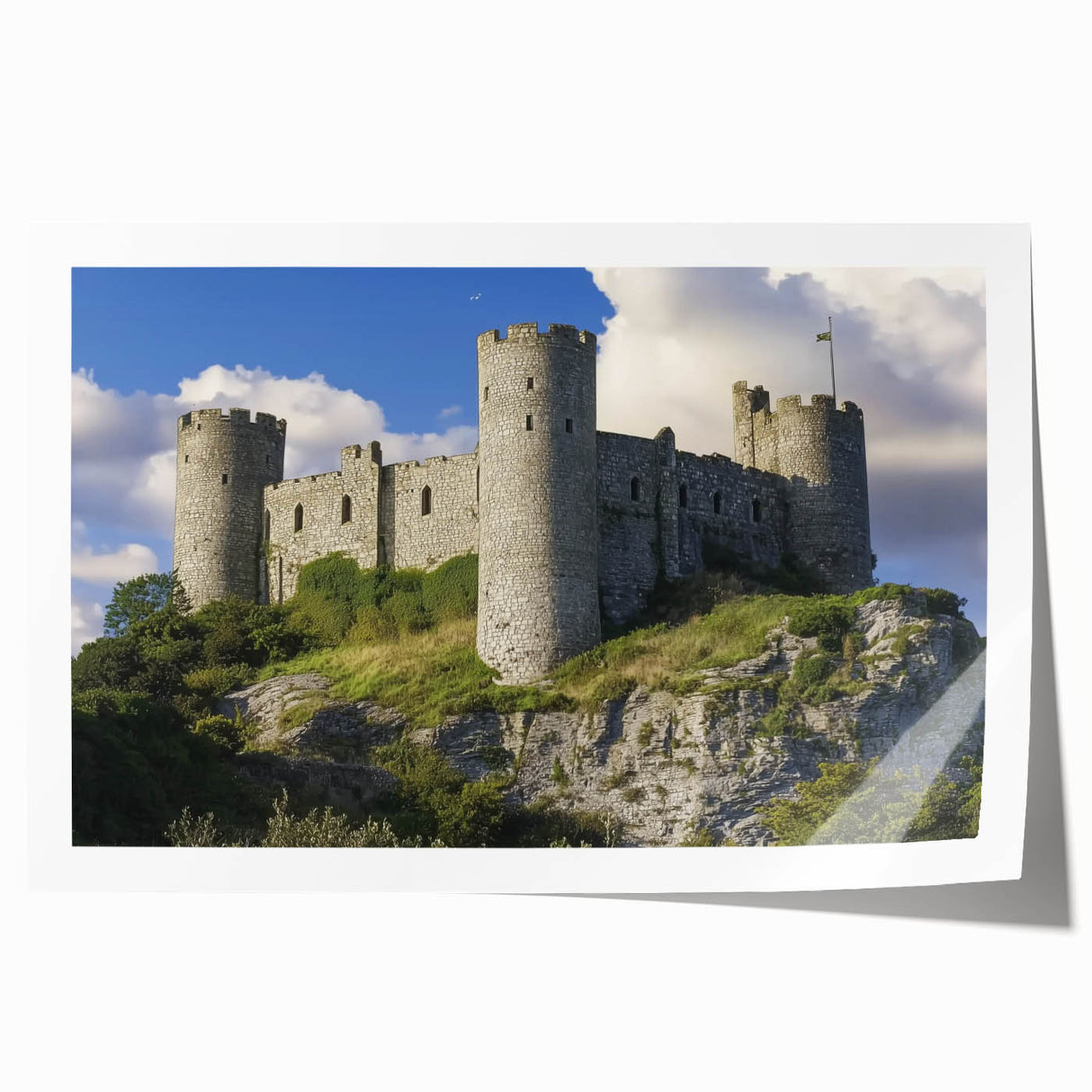 Landscape print showcasing a vibrant castle scene, featuring lush greenery and a clear blue sky, rolled and ready for display in a protective cardboard tube.
