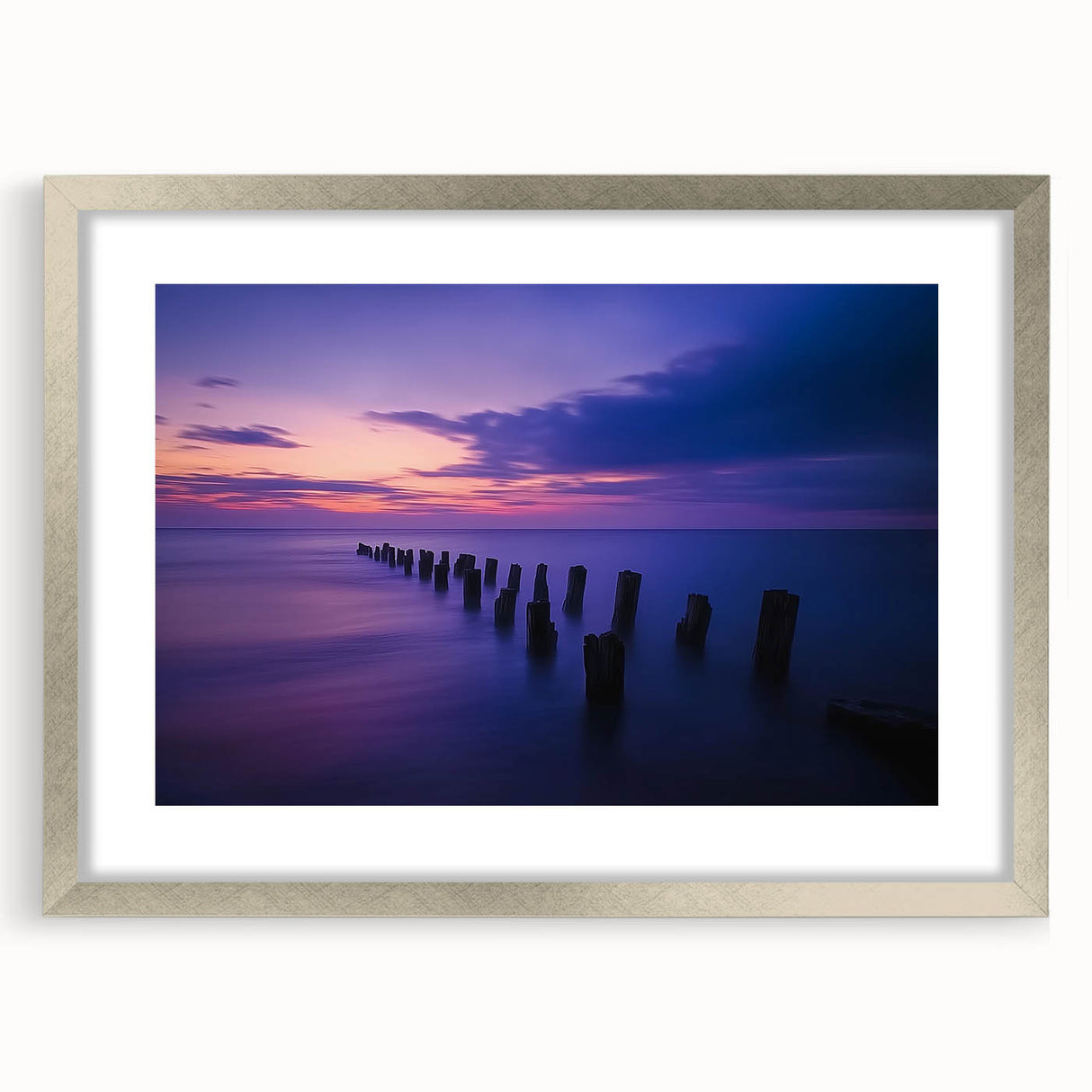 Framed landscape artwork depicting serene beach scenery with soft waves and a clear sky, enclosed in a modern silver mat for an elegant presentation.